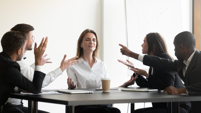 While stressed colleagues screaming to young businesswoman she meditating