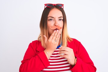 Young beautiful woman holding fanny party mustache standing over isolated white background cover mouth with hand shocked with shame for mistake, expression of fear, scared in silence, secret concept