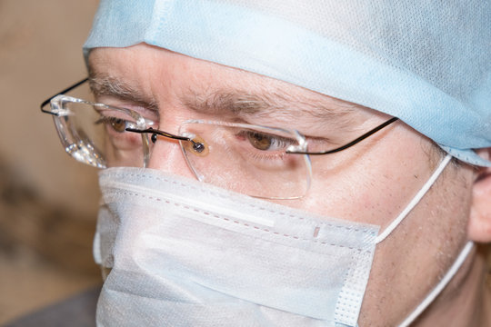 Male Doctor Of Middle Age 50 Years Old In A Protective Mask With Glasses For Vision Close Up Portrait