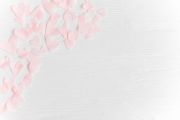 Cute pink pastel hearts on white wooden background with space for text. Flat lay. Pink paper heart cutouts on white background, cute gentle image,  greeting card or wedding invitation