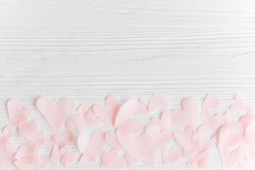 Cute pink pastel hearts on white wooden background with space for text. Flat lay. Pink paper heart cutouts on white background, cute gentle image,  greeting card or wedding invitation