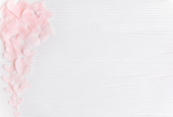 Cute pink pastel hearts on white wooden background with space for text. Flat lay. Happy valentines day. Pink paper heart cutouts on white,  gentle image,  greeting card.
