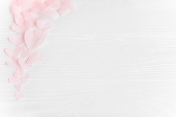Happy valentines day. Cute pink pastel hearts on white wooden background with space for text.  Pink paper heart cutouts border on white, gentle image,  greeting card. Selective focus