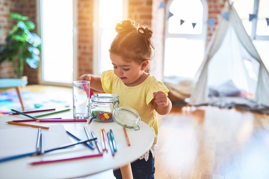 Beautiful toddler standing playing with chocolate colored balls on the table at kindergarten