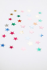 Colorful stars confetti or glitter on white background. Party backdrop. Stylish atmospheric image. Happy birthday concept. Holiday decorations. Magic and Christmas.