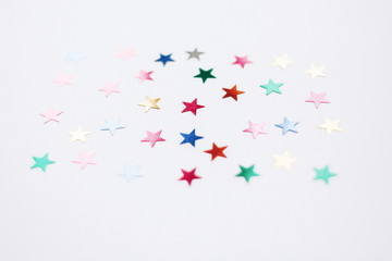 Fototapeta na wymiar Colorful stars confetti or glitter on white background. Party backdrop. Stylish atmospheric image. Happy birthday concept. Holiday decorations. Magic and Christmas.