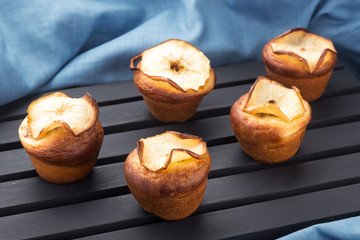 Cupcakes, muffins on a black table with a blue napkin. Cupcakes, muffins on a wooden board and a black wooden table. Fresh French Baked Cupcakes. Warm Fresh Buttery Rolls.