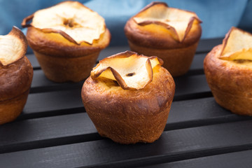 Cupcakes, muffins on a black table with a blue napkin. Cupcakes, muffins on a wooden board and a black wooden table. Fresh French Baked Cupcakes. Warm Fresh Buttery Rolls.