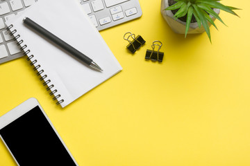 Yellow desk office with laptop, smartphone and other work supplies with cup of coffee. Top view with copy space for input the text. Designer workspace on desk table essential elements on flat lay