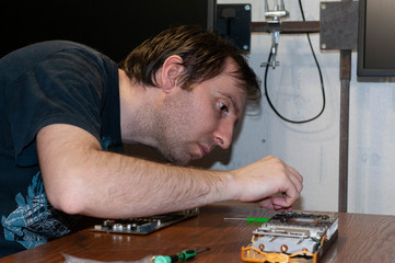 handsome man with screwdriver fixing graphics card on wooden table in home improvement