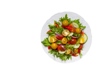 Fresh vegetables: yellow and red tomatoes, purple onions, green lettuce and cucumbers, red pepper on a plate. Isolated on a white background. View from above.