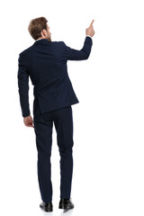 young businessman in navy blue suit pointing finger to side