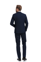 young businessman in navy blue suit smiling and walking