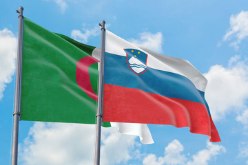 Slovenia and Algeria flags waving in the wind against white cloudy blue sky together. Diplomacy concept, international relations.