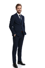 happy young businessman holding hands in pockets and smiling