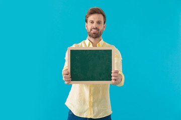 Positive casual man smiling and holding a blackboard