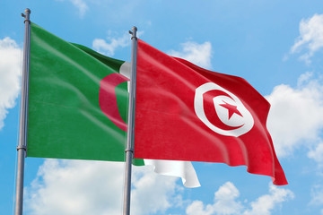 Tunisia and Algeria flags waving in the wind against white cloudy blue sky together. Diplomacy concept, international relations.