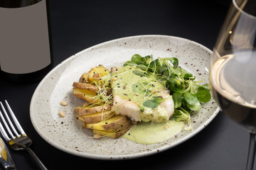Oven-baked fish. Grilled fish with potatoes, vegetables on a plate on a white table. Delicious roasted fish and potatoes on a white wooden table. Space for text
