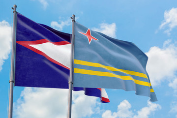Aruba and American Samoa flags waving in the wind against white cloudy blue sky together. Diplomacy...
