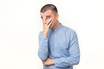 Shocked and terrified young man covering his face by hand and looking at camera