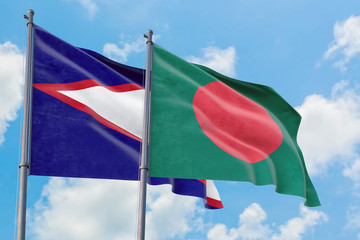 Bangladesh and American Samoa flags waving in the wind against white cloudy blue sky together. Diplomacy concept, international relations.