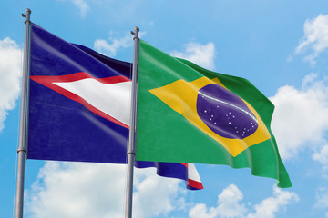 Brazil and American Samoa flags waving in the wind against white cloudy blue sky together....