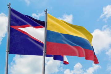 Colombia and American Samoa flags waving in the wind against white cloudy blue sky together. Diplomacy concept, international relations.