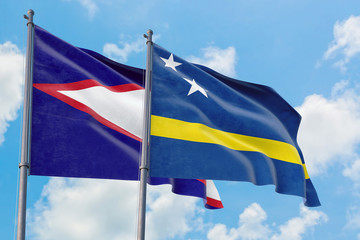 Curacao and American Samoa flags waving in the wind against white cloudy blue sky together. Diplomacy concept, international relations.