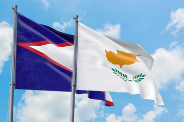 Cyprus and American Samoa flags waving in the wind against white cloudy blue sky together. Diplomacy concept, international relations.