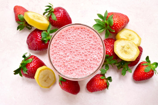 Delicious strawberry banana smoothie in a glass with ingredients for making. Top view with copy space.