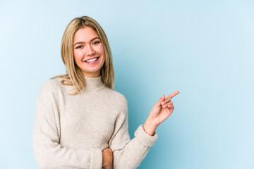 Young blonde caucasian woman isolated smiling cheerfully pointing with forefinger away.