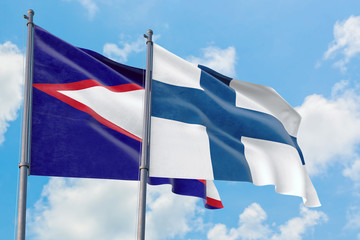 Finland and American Samoa flags waving in the wind against white cloudy blue sky together. Diplomacy concept, international relations.