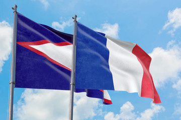 France and American Samoa flags waving in the wind against white cloudy blue sky together. Diplomacy concept, international relations.