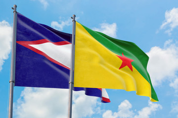 French Guiana and American Samoa flags waving in the wind against white cloudy blue sky together. Diplomacy concept, international relations.