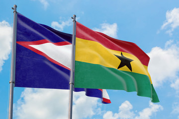 Ghana and American Samoa flags waving in the wind against white cloudy blue sky together. Diplomacy concept, international relations.