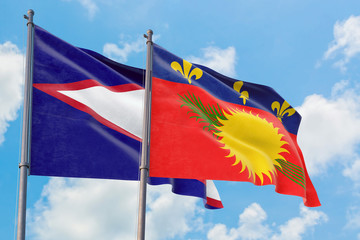 Guadeloupe and American Samoa flags waving in the wind against white cloudy blue sky together. Diplomacy concept, international relations.