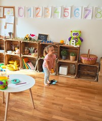 Beautiful blond toddler girl standing at kindergarten