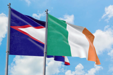 Ireland and American Samoa flags waving in the wind against white cloudy blue sky together. Diplomacy concept, international relations.