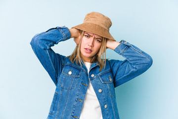 Young blonde caucasian woman isolated covering ears with hands trying not to hear too loud sound.