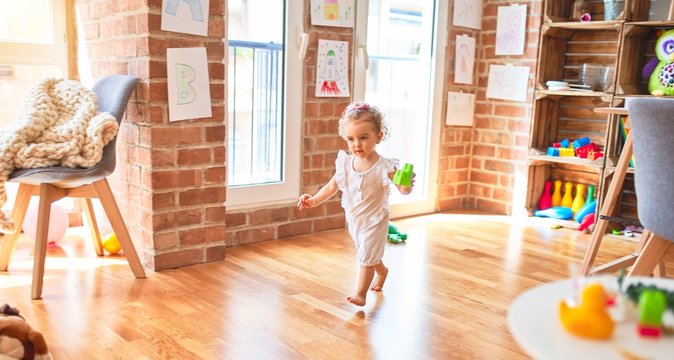 Beautiful caucasian infant playing with toys at colorful playroom. Happy and playful at kindergarten.