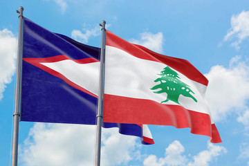 Lebanon and American Samoa flags waving in the wind against white cloudy blue sky together. Diplomacy concept, international relations.