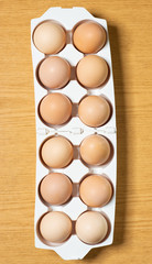 Eggs laid in plastic tray, wooden background.