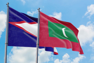 Maldives and American Samoa flags waving in the wind against white cloudy blue sky together. Diplomacy concept, international relations.
