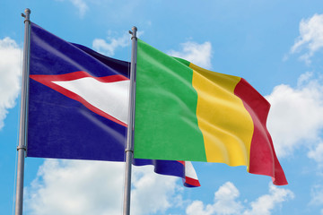 Mali and American Samoa flags waving in the wind against white cloudy blue sky together. Diplomacy...