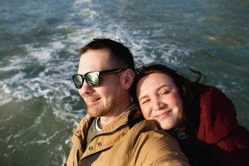 Happy couple takes a selfie in the background of the aquamarine spring sea.