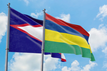 Mauritius and American Samoa flags waving in the wind against white cloudy blue sky together. Diplomacy concept, international relations.