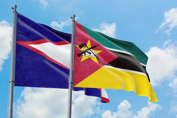 Mozambique and American Samoa flags waving in the wind against white cloudy blue sky together. Diplomacy concept, international relations.