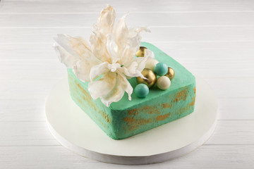 Delicious festive homemade cake. Green chocolate cake. A chocolate cake on a white plate with slice cut out. Delicious homemade cake with sugar flowers. Close up view. Space for text