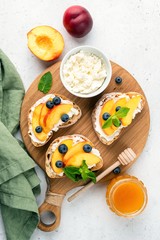 Sweet Bruschetta With Ricotta Cheese, Peach, Blueberries And Honey On Wooden Serving Board. Table Top View