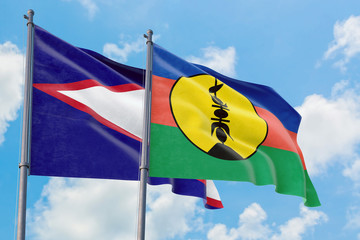 New Caledonia and American Samoa flags waving in the wind against white cloudy blue sky together....